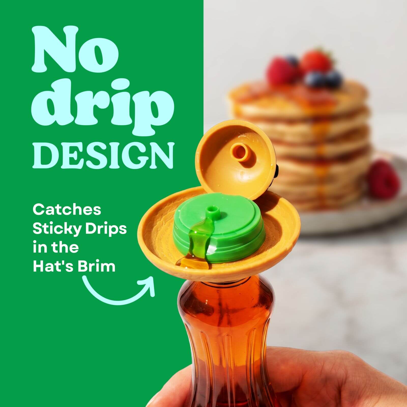 No-drip syrup and honey dispenser with a green cap held by a hand, next to a stack of pancakes with syrup on a plate.
